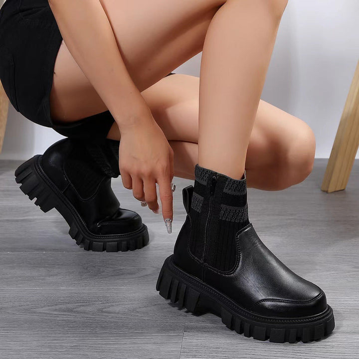 Schwarze Chelsea-Boots mit Strickschaft und dicker Plateausohle, getragen von Frau in Hocke